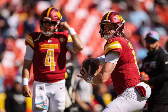 LANDOVER, MD - OCTOBER 09: Carson Wentz #11 of the Washington Commanders warms up as Taylor Heinicke #4 looks on before the game against the Tennessee Titans at FedExField on October 9, 2022 in Landover, Maryland. (Photo by Scott Taetsch/Getty Images)