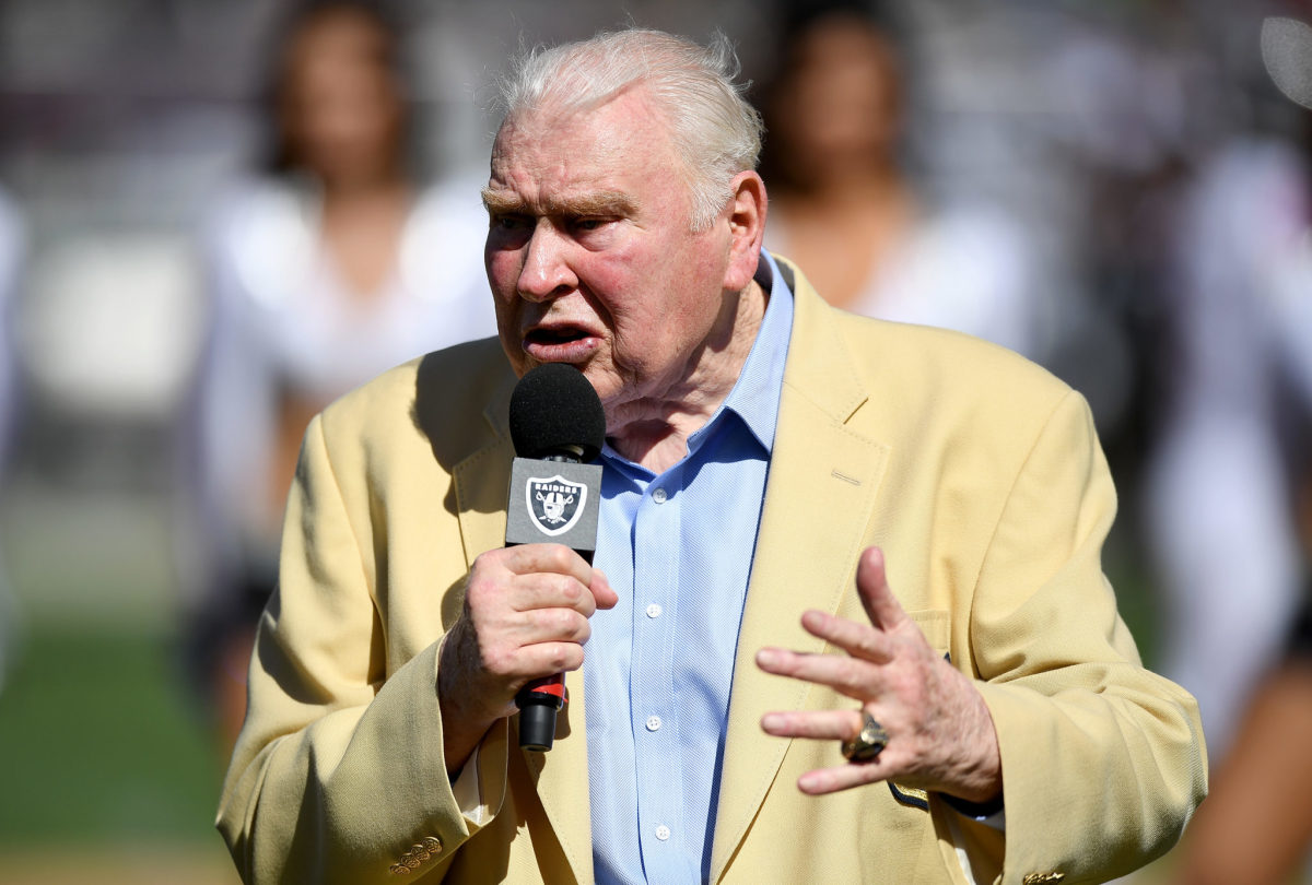 John Madden holds a microphone and speaks before a game.