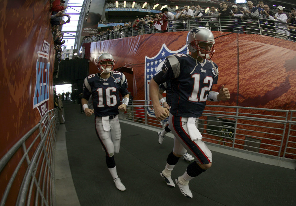 Matt Cassel and Tom Brady run out of the tunnel and onto the field.
