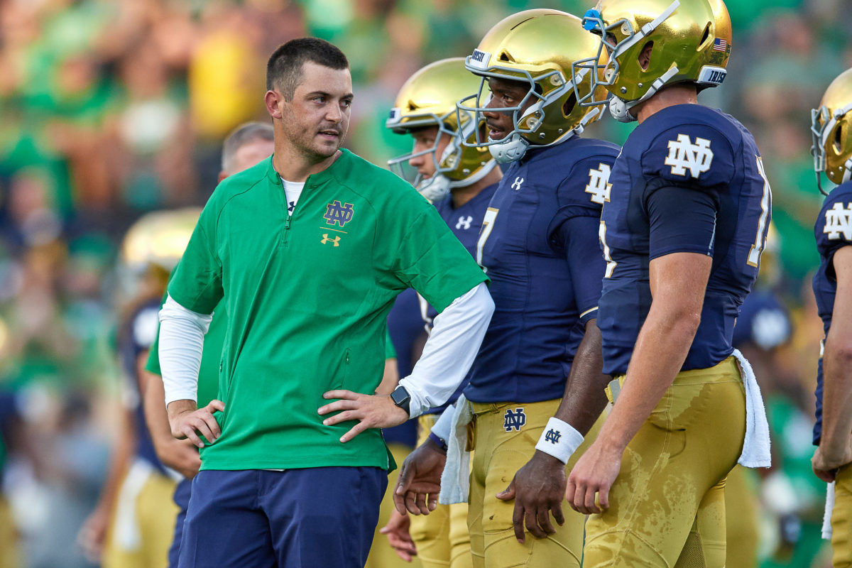 Notre Dame offensive coordinator Tommy Rees address players on the sidelines.
