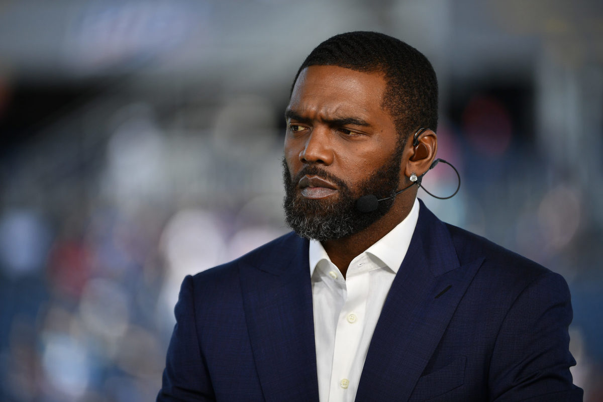 Former NFL wide receiver Randy Moss looks on.