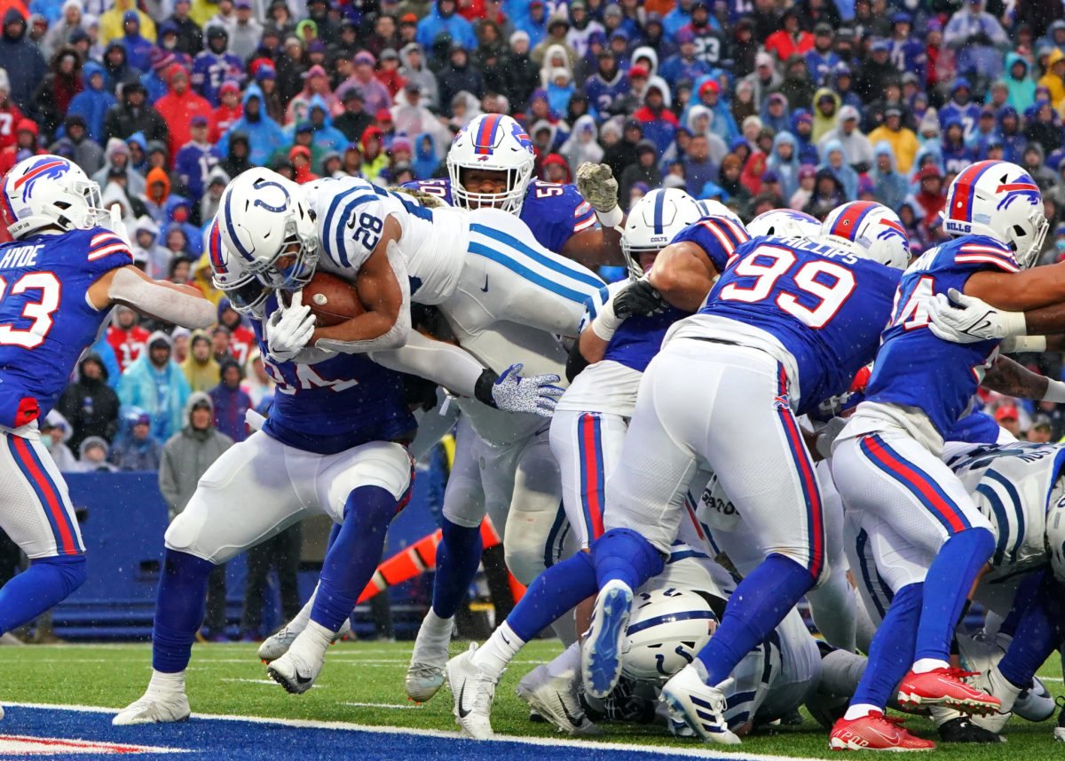 Colts running back Jonathan Taylor dives into the end zone while surrounded by Bills tacklers.