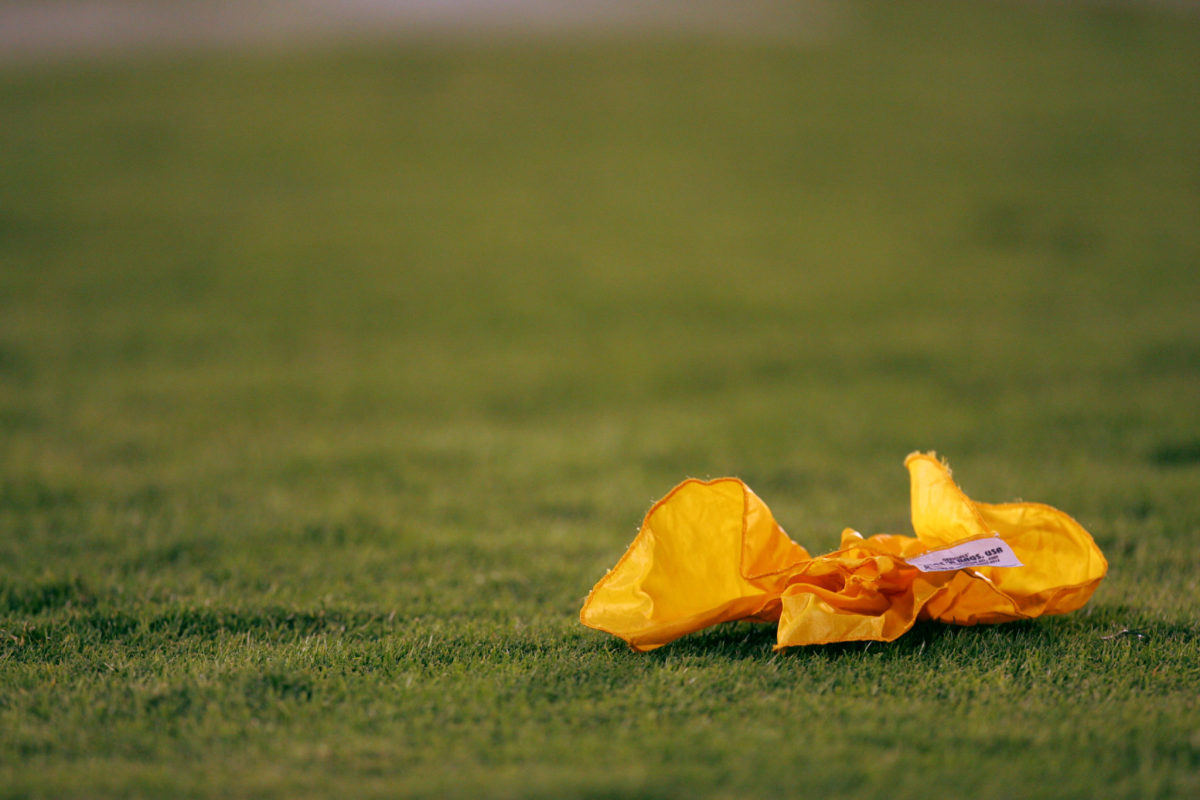 A closeup of a penalty flag on a football field.
