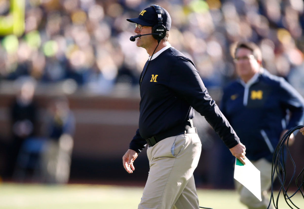 Jim Harbaugh walking onto the field during a football game.