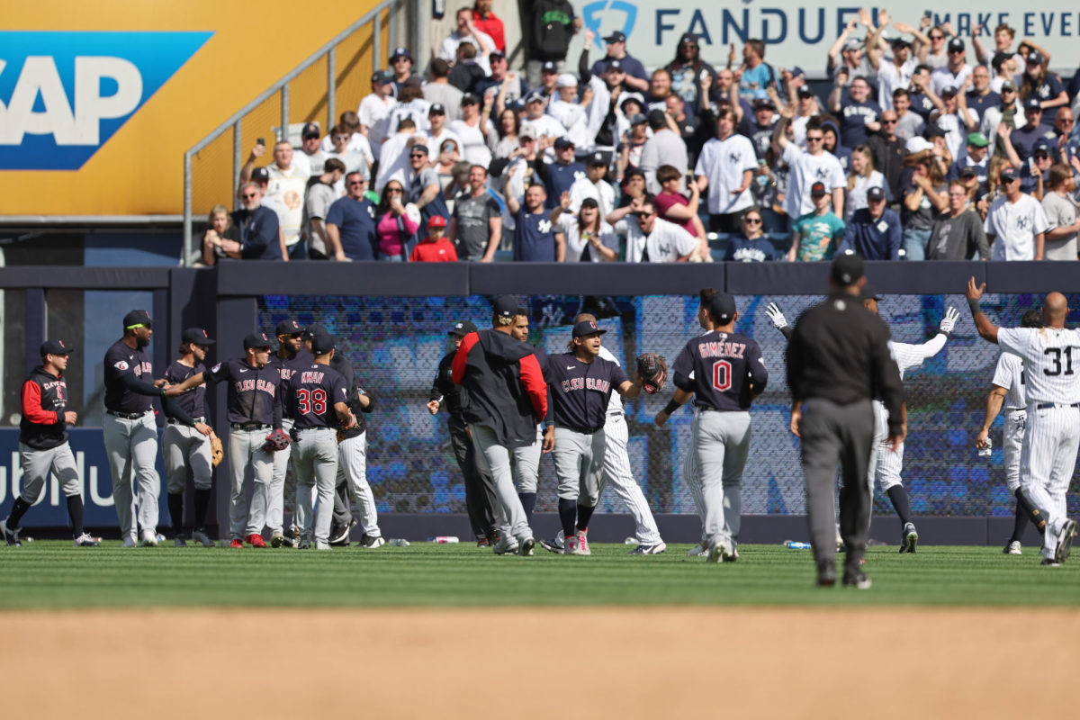 Guardians and Yankees players in the outfield after a conflict with fans.