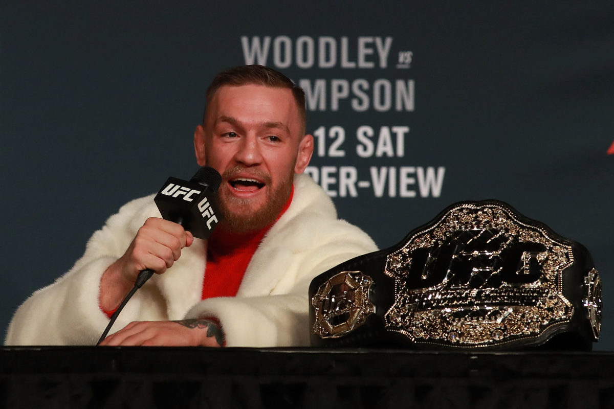 Conor McGregor talking into a microphone next to his UFC belt.