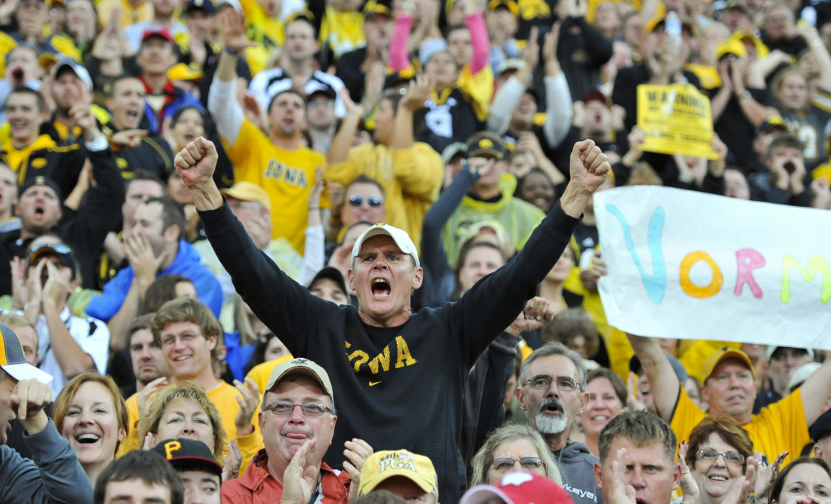 An Iowa Hawkeyes fan celebrating in the stands during a football game.