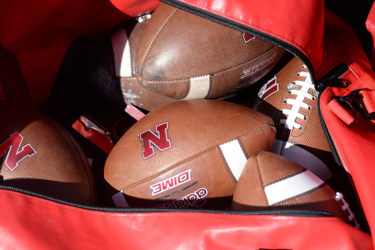 A bag of footballs with the logo of the Nebraska Cornhuskers.