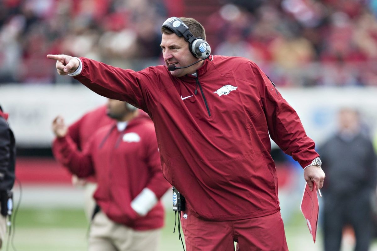 Bret Bielema pointing while wearing a red Arkansas jumpsuit.