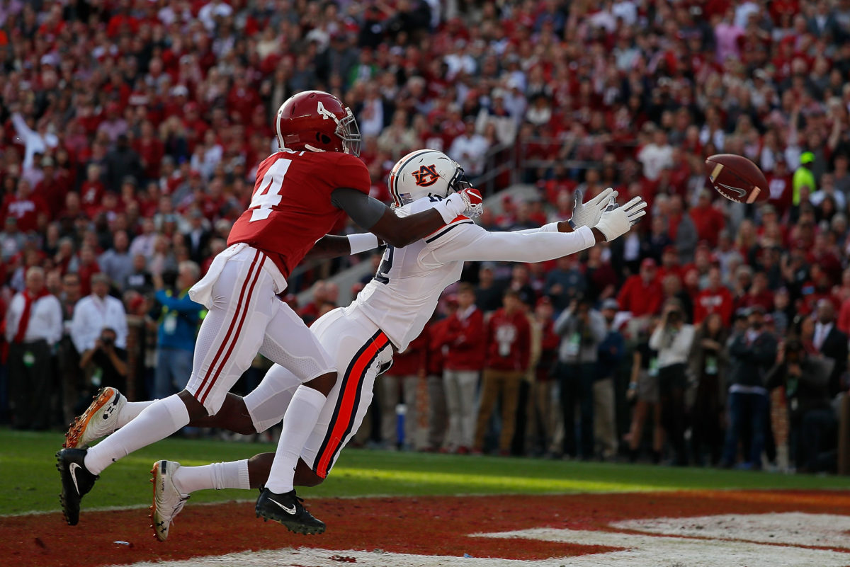 Alabama receiver Jerry Jeudy and an Auburn defensive back dive for a pass.