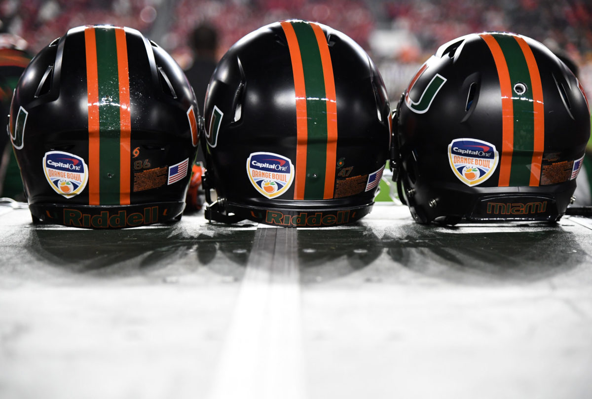 A closeup of Miami football helmets sitting on a bench.