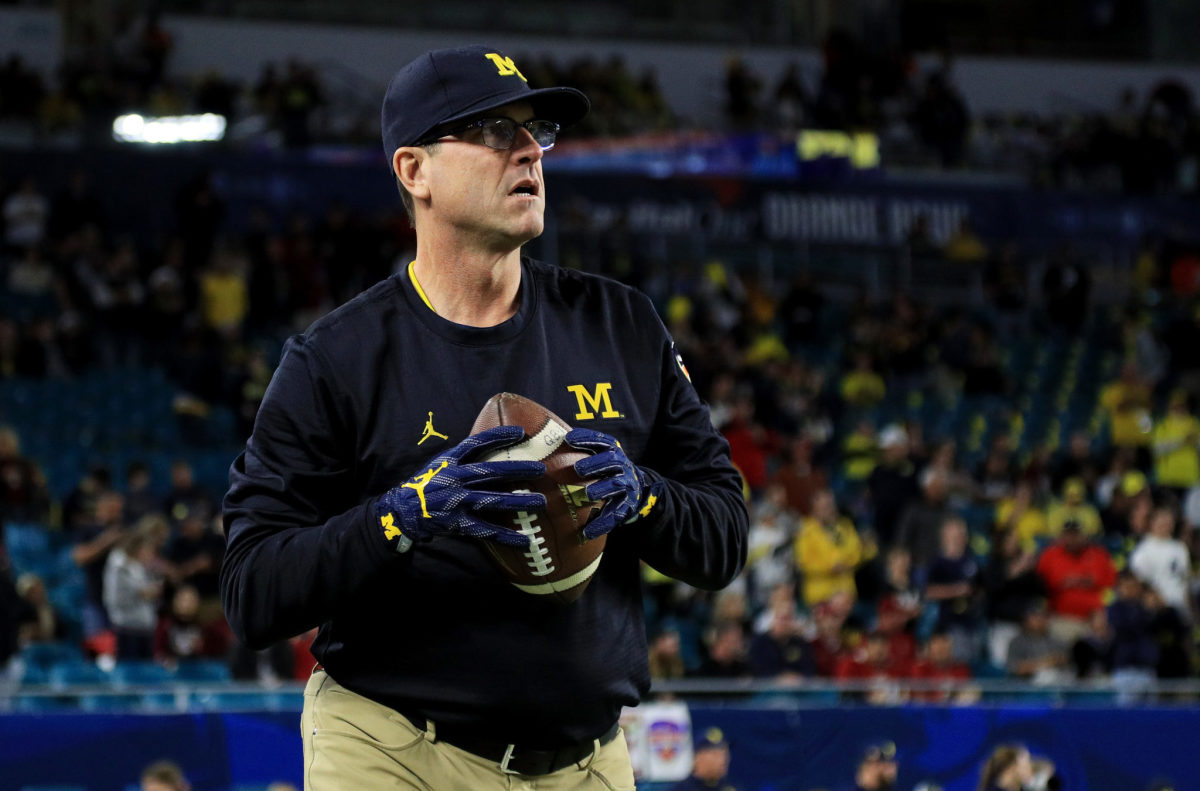 Jim Harbaugh throwing a pass during warmups before a Michigan football game.