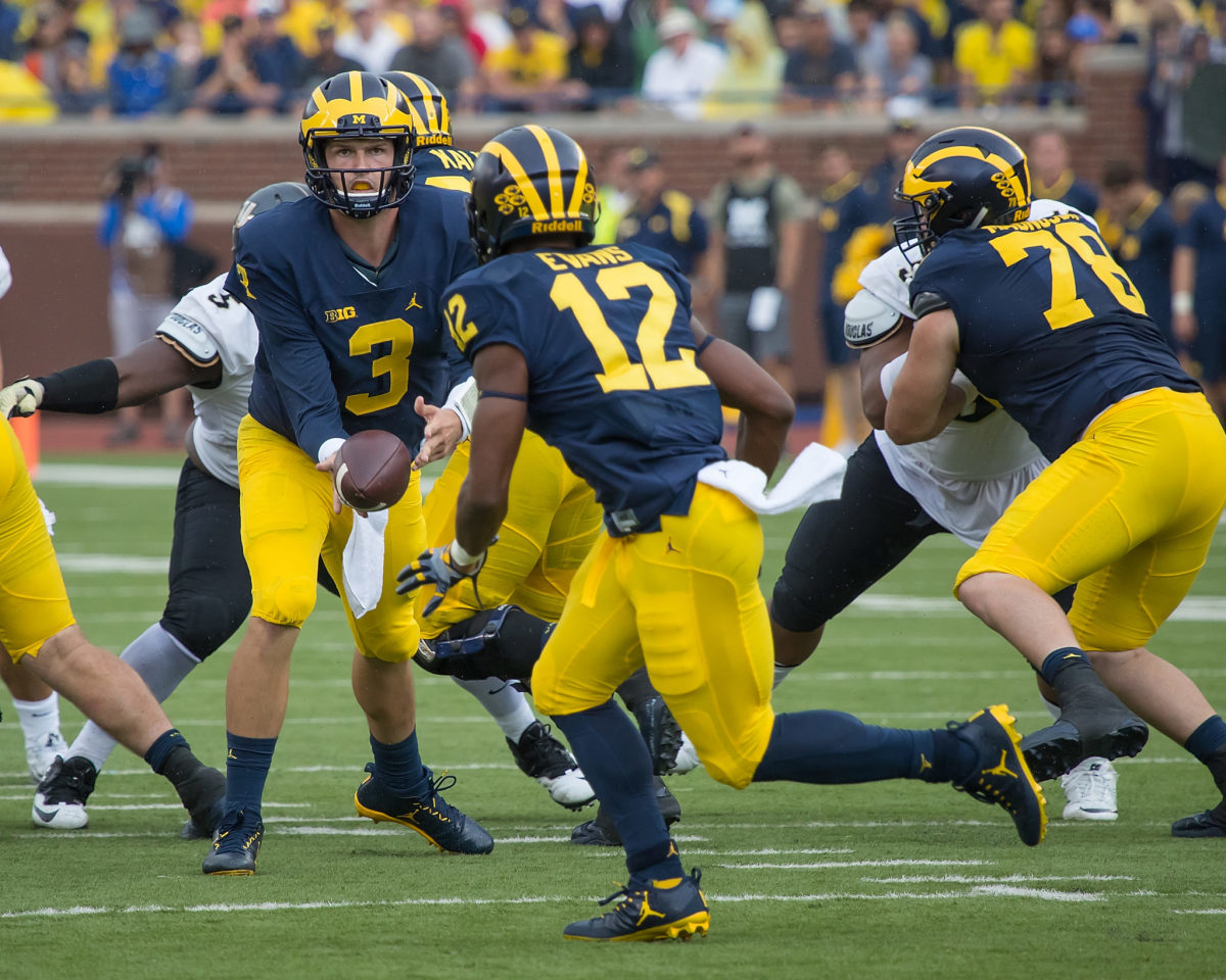 Quarterback Wilton Speight of the Michigan Wolverines flips the football to running back Chris Evans #12 in the third quarter during a college football game against the UCF Knights at Michigan Stadium.