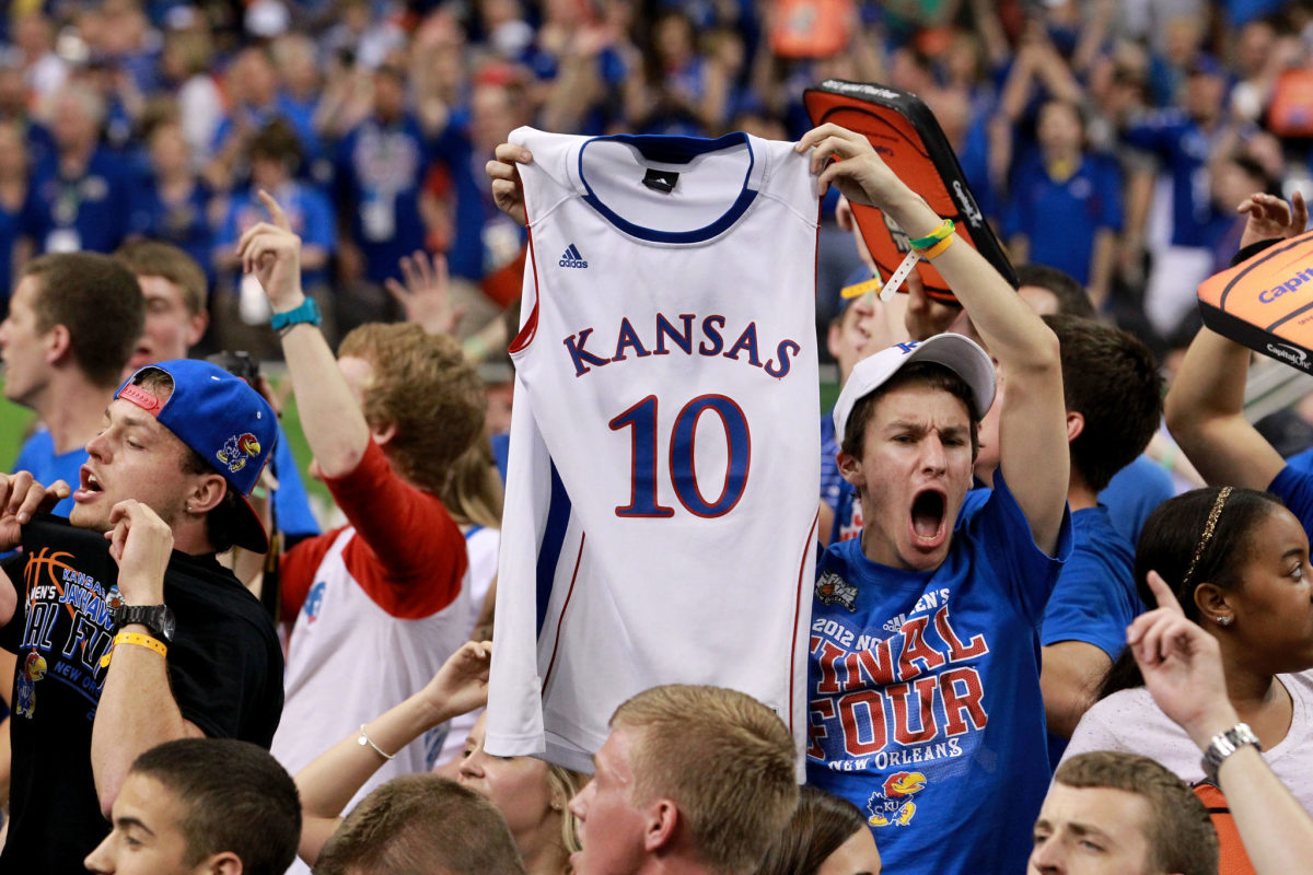 A Kansas fan holding up a white Kansas #10 jersey.