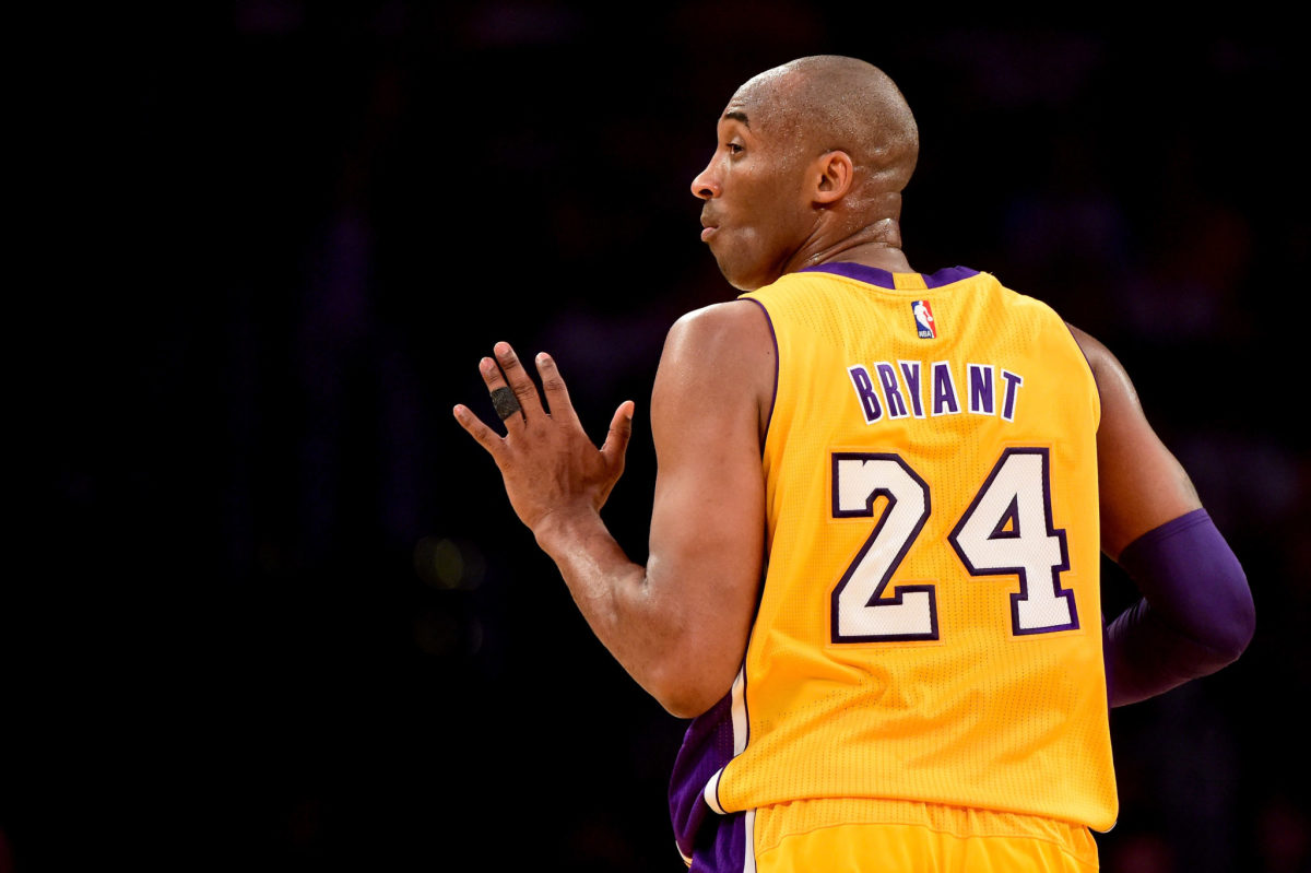 Kobe Bryant holding out five fingers as he runs up the floor.