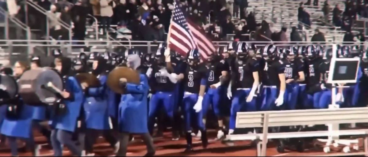 Four-star wide receiver A.J. Henning carries American flag onto field.