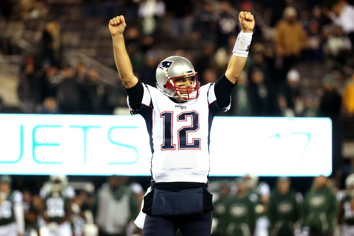 New England Patriots QB Tom Brady raising his arms in triumph after an NFL win.