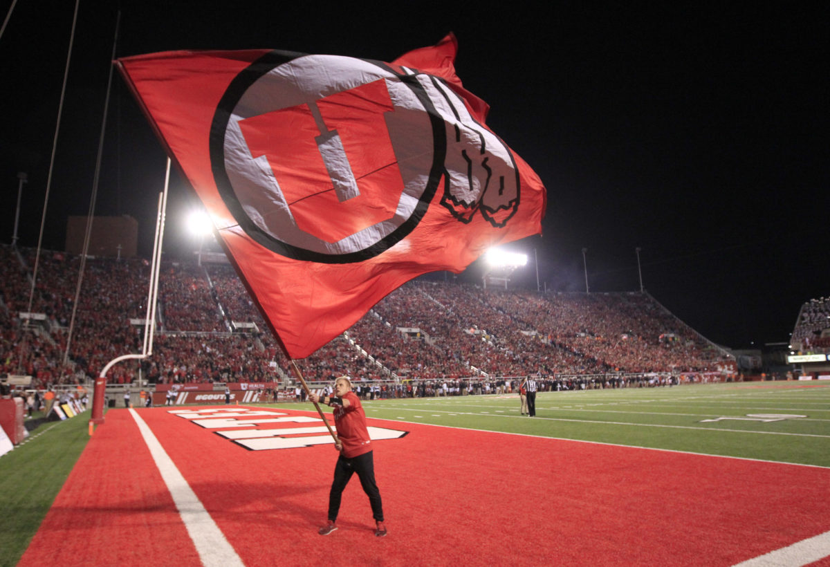 A man waving a flag with Utah's logo on it.