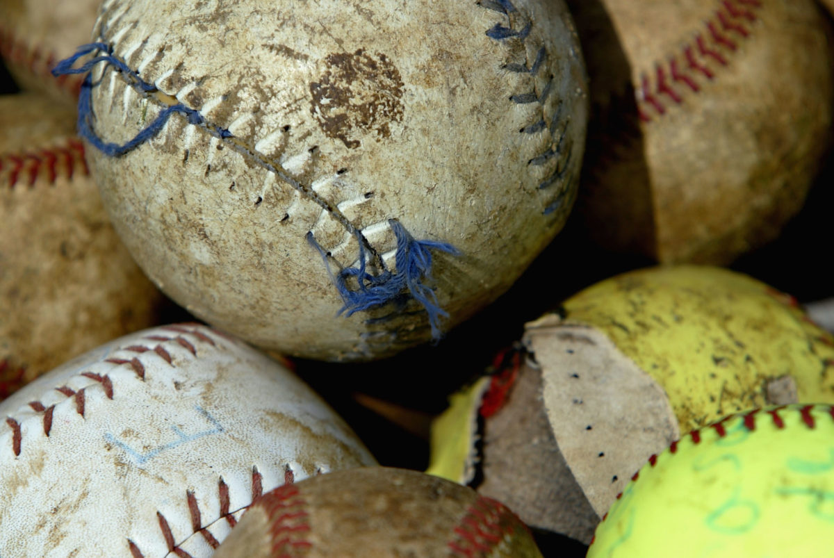 A pile of softballs and baseballs that have been worn down.