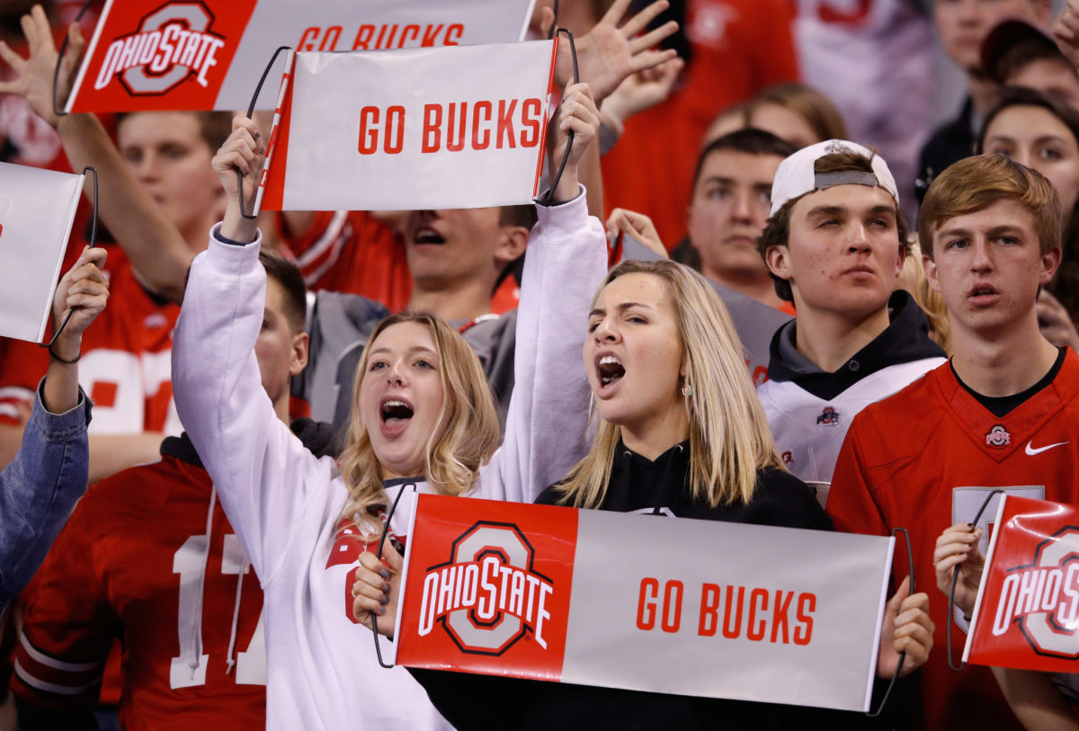 Ohio State fans holding Go Bucks signs during a football game.