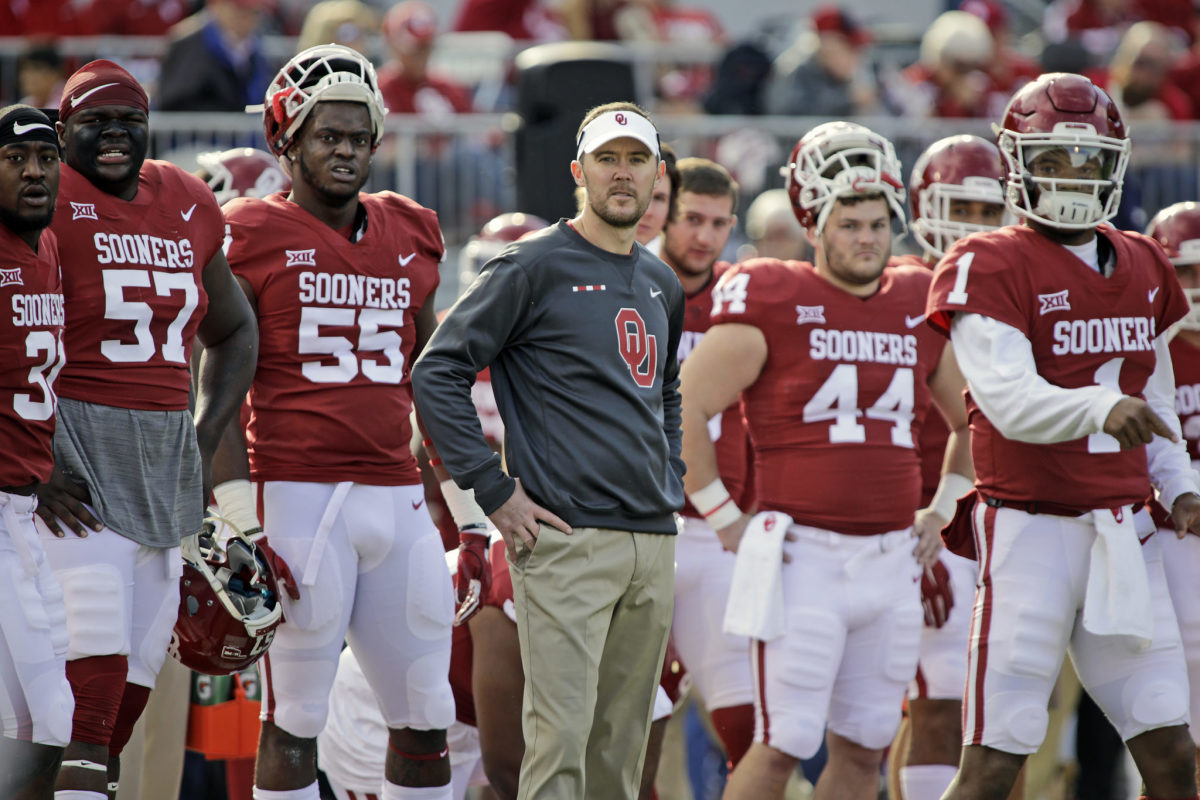 Lincoln Riley standing with his Oklahoma football players on the sideline.