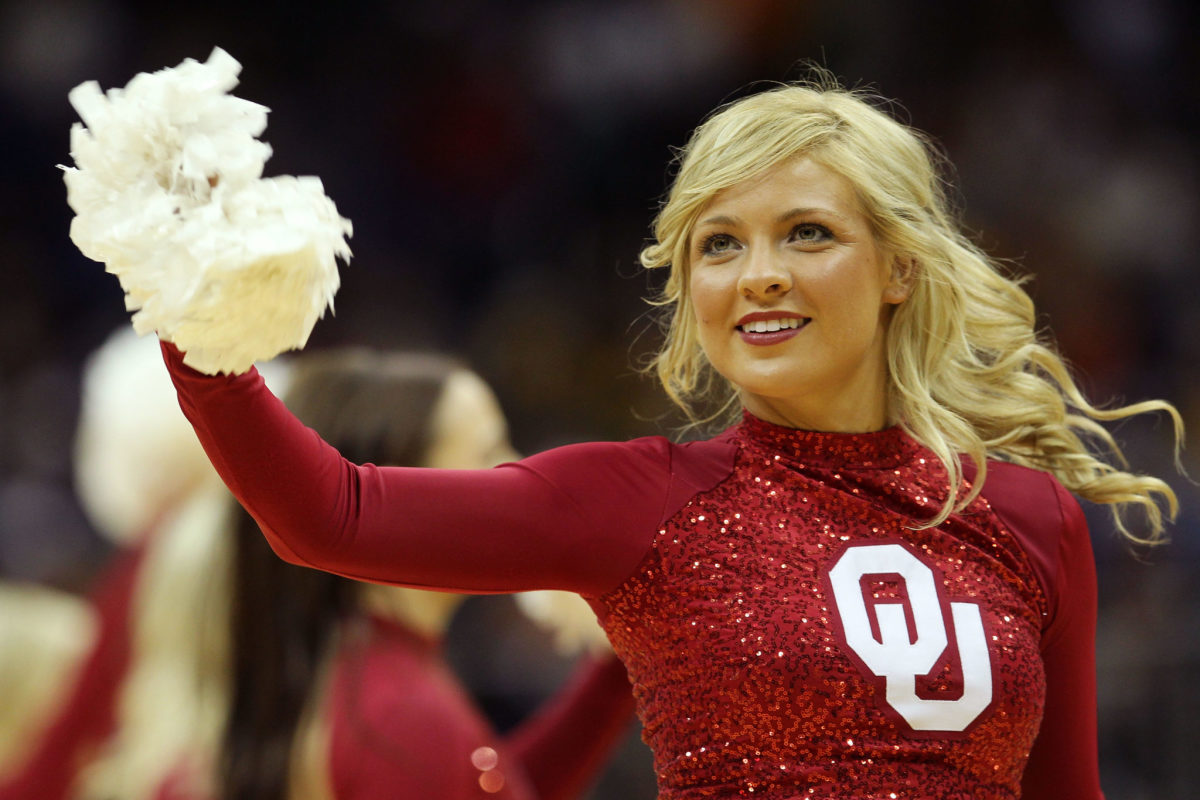 A closeup of an Oklahoma cheerleader waving a pompom.