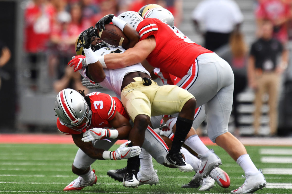 Ohio State players tackling an Army player carrying the football.