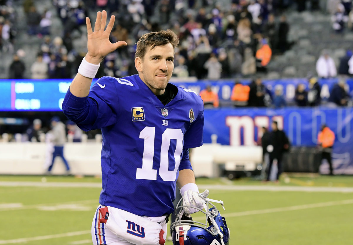 New York Giants QB Eli Manning waving as he walks off the field.