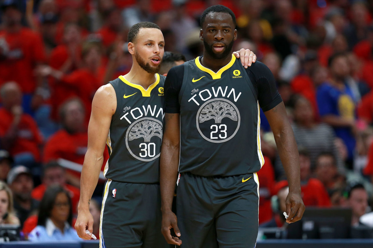 Steph Curry with his arm wrapped around Draymond Green