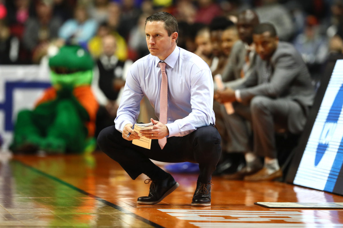 Mike White crouches on sideline while coaching Florida.