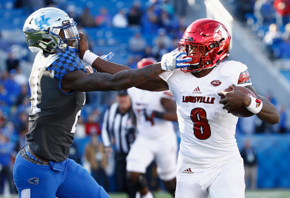 Louisville's Lamar Jackson stiff arms a Kentucky defender.