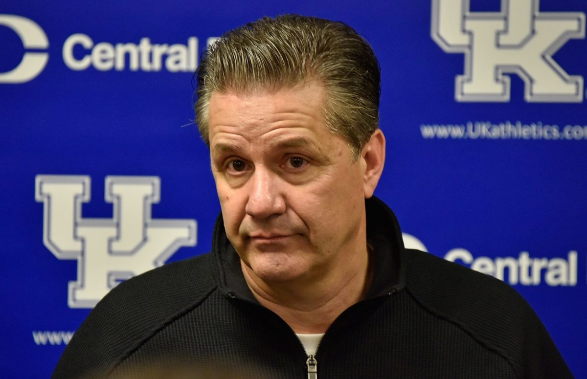 A closeup of Coach John Calipari in front of a blue Kentucky background.