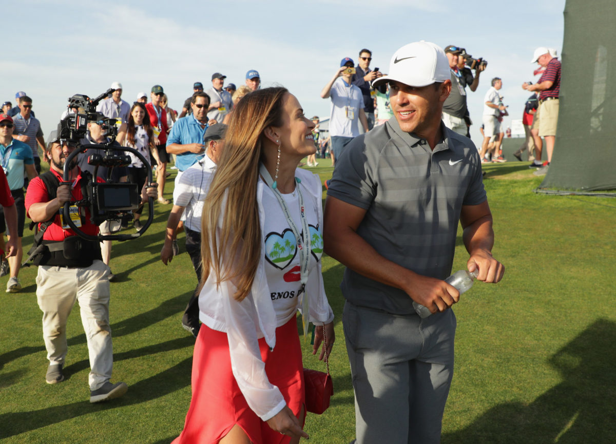 Brooks Koepka walking on the golf course with his girlfriend.
