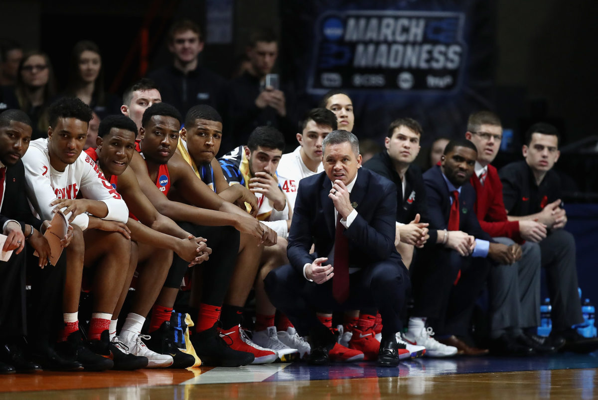 Ohio State basketball coach Chris Holtmann squatting on the sideline.
