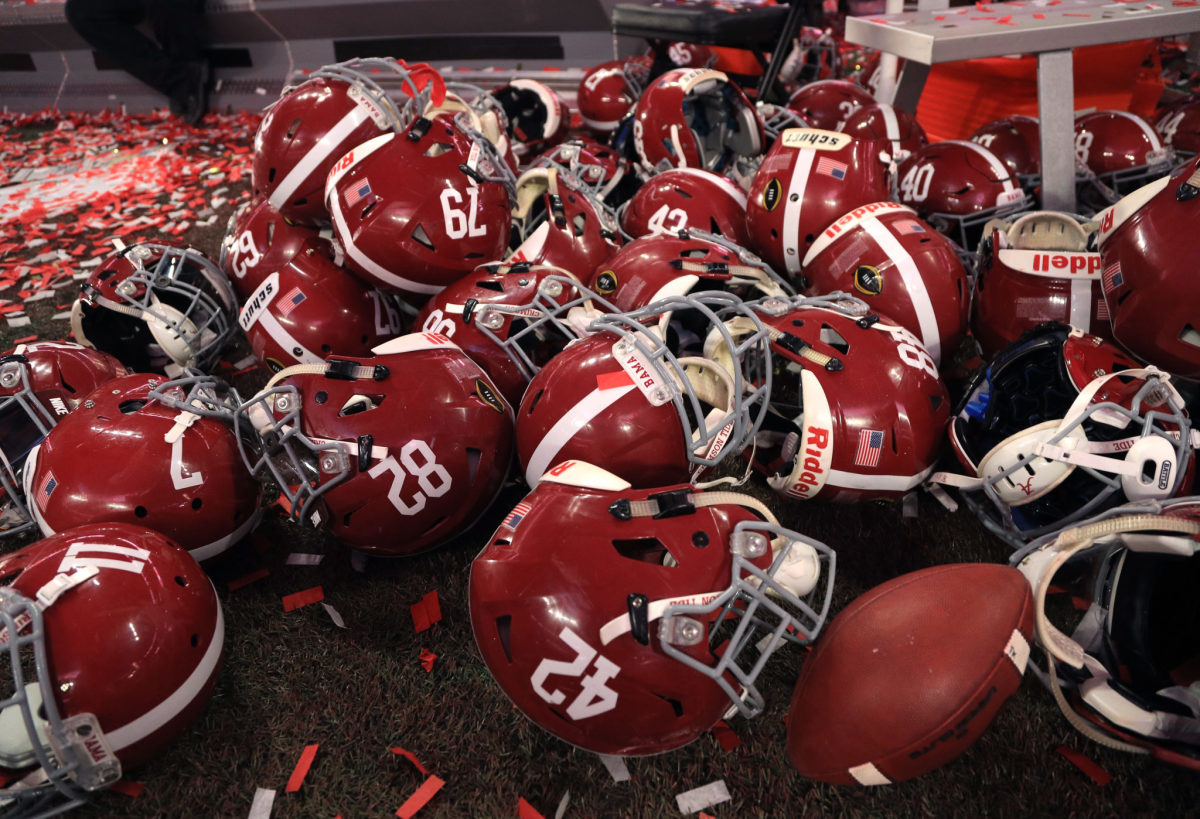 Multiple Alabama football helmets laying on the ground.