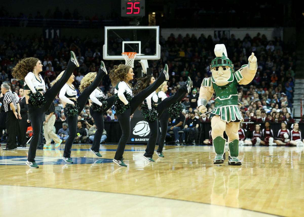 The Michigan State Spartans mascot performing with the cheerleaders during a basketball game.