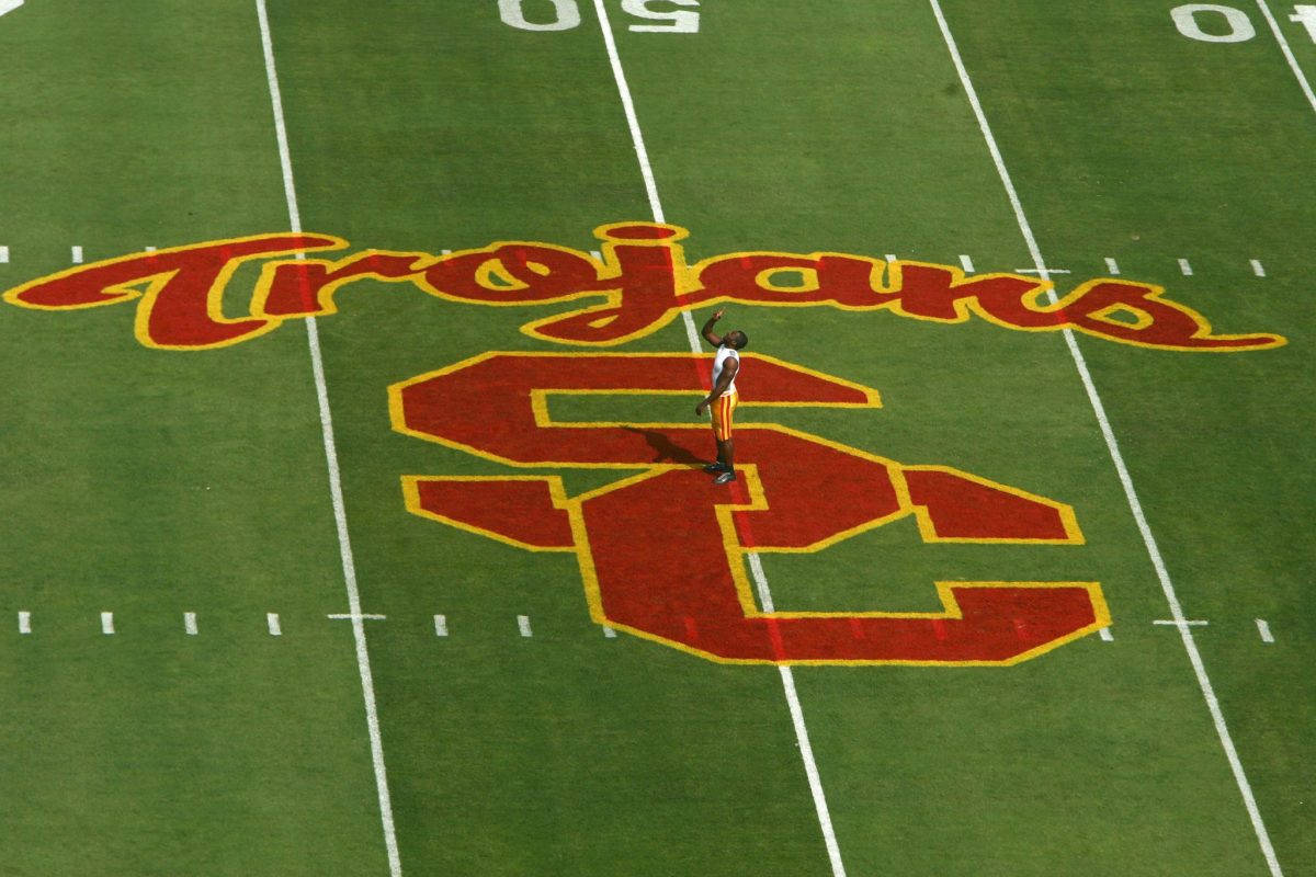 A player stading at the 50 yard line of USC's football field.