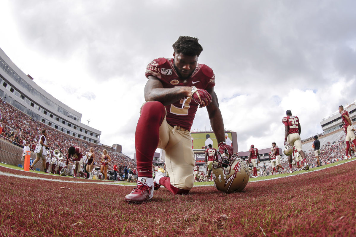 Florida State star Cam Akers takes a knee before a game.