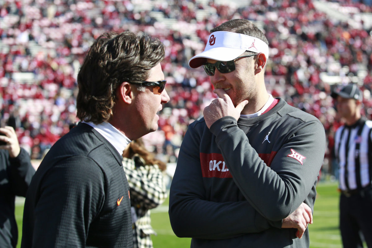 Mike Gundy and Lincoln Riley speak on the field before a game.