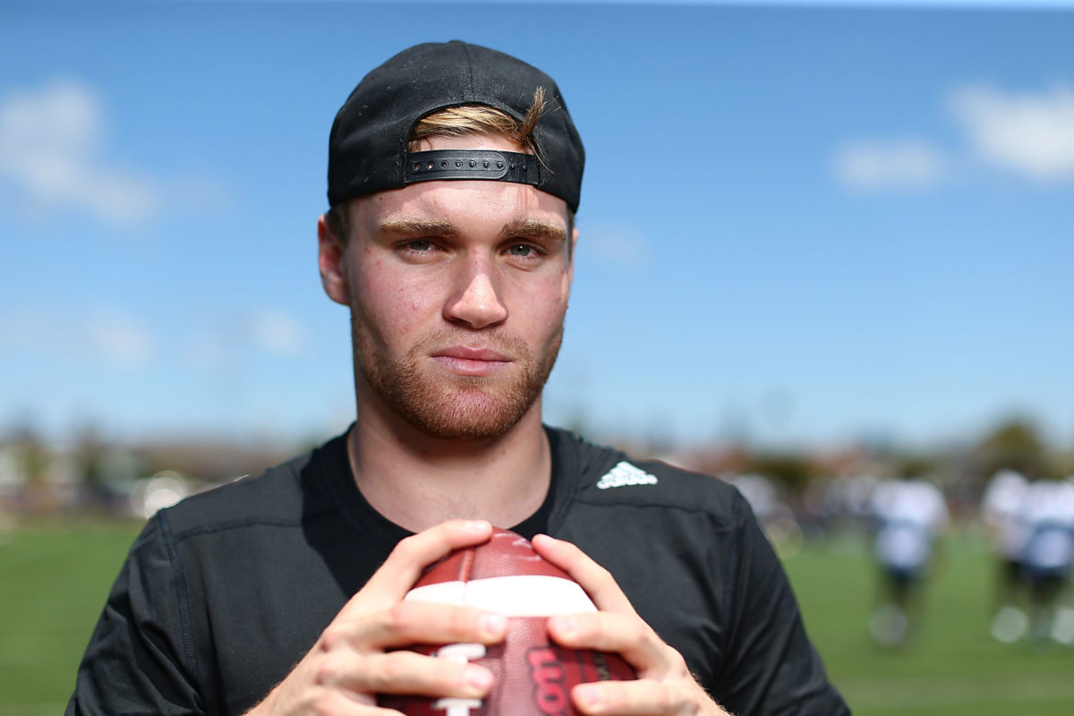 tate martell holds a football during a camp