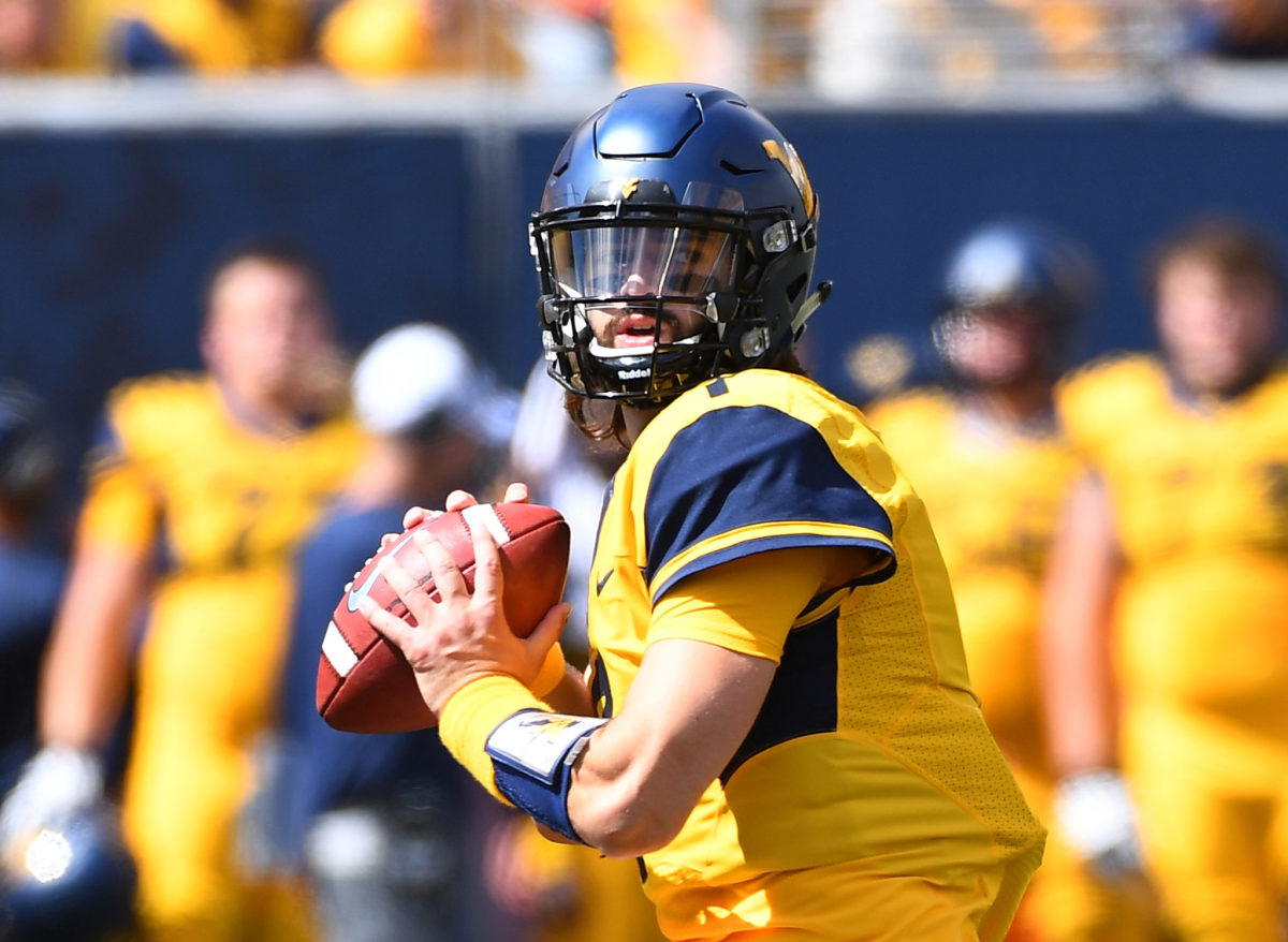 A closeup of Will Grier dropping back for a pass.