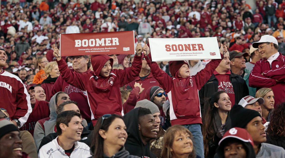 Two Oklahoma Sooner fans holding up signs during a football game.