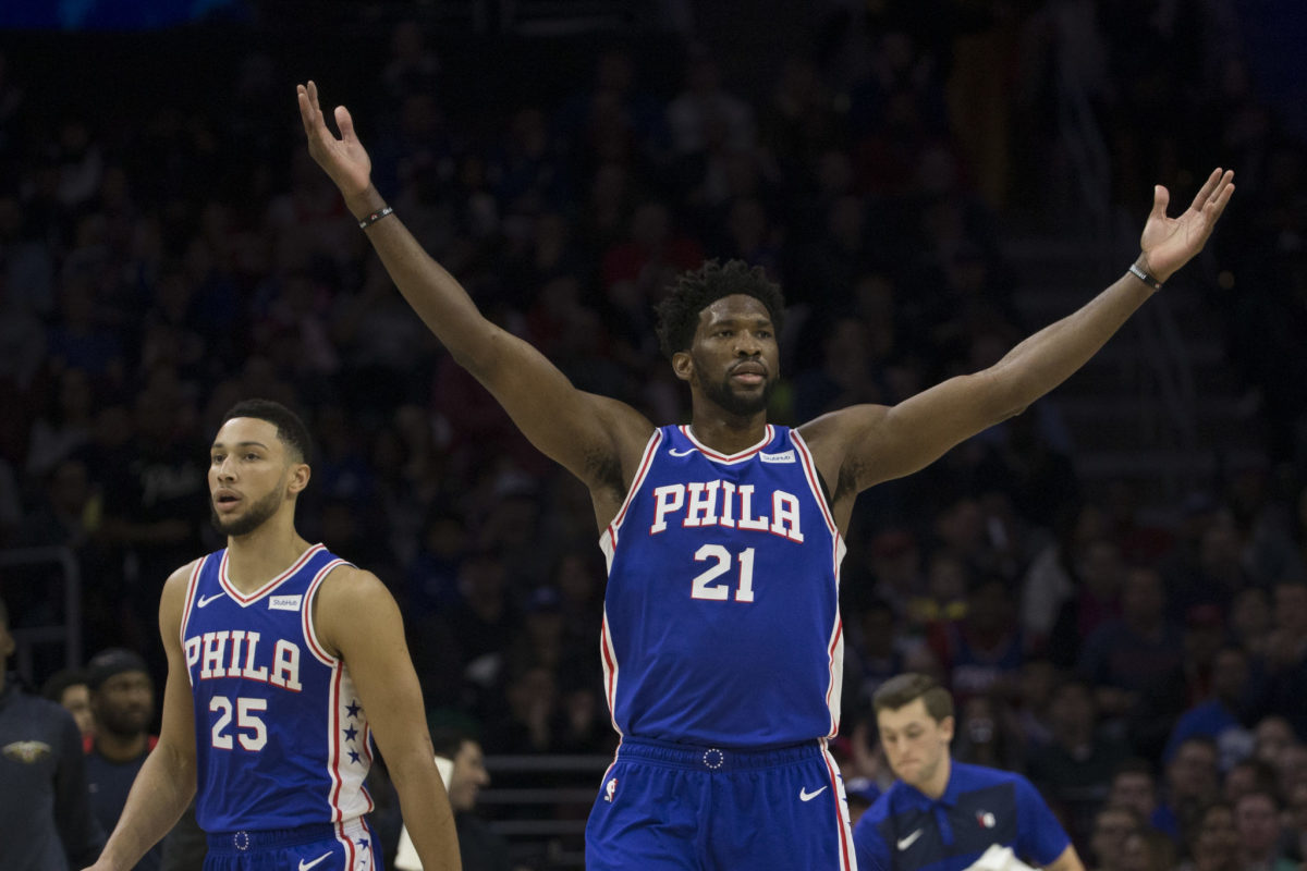 Joel Embiid raising his arms during a Philadelphia 76ers game. He reportedly approves of Mike D'Antoni as potential next Sixers coach.