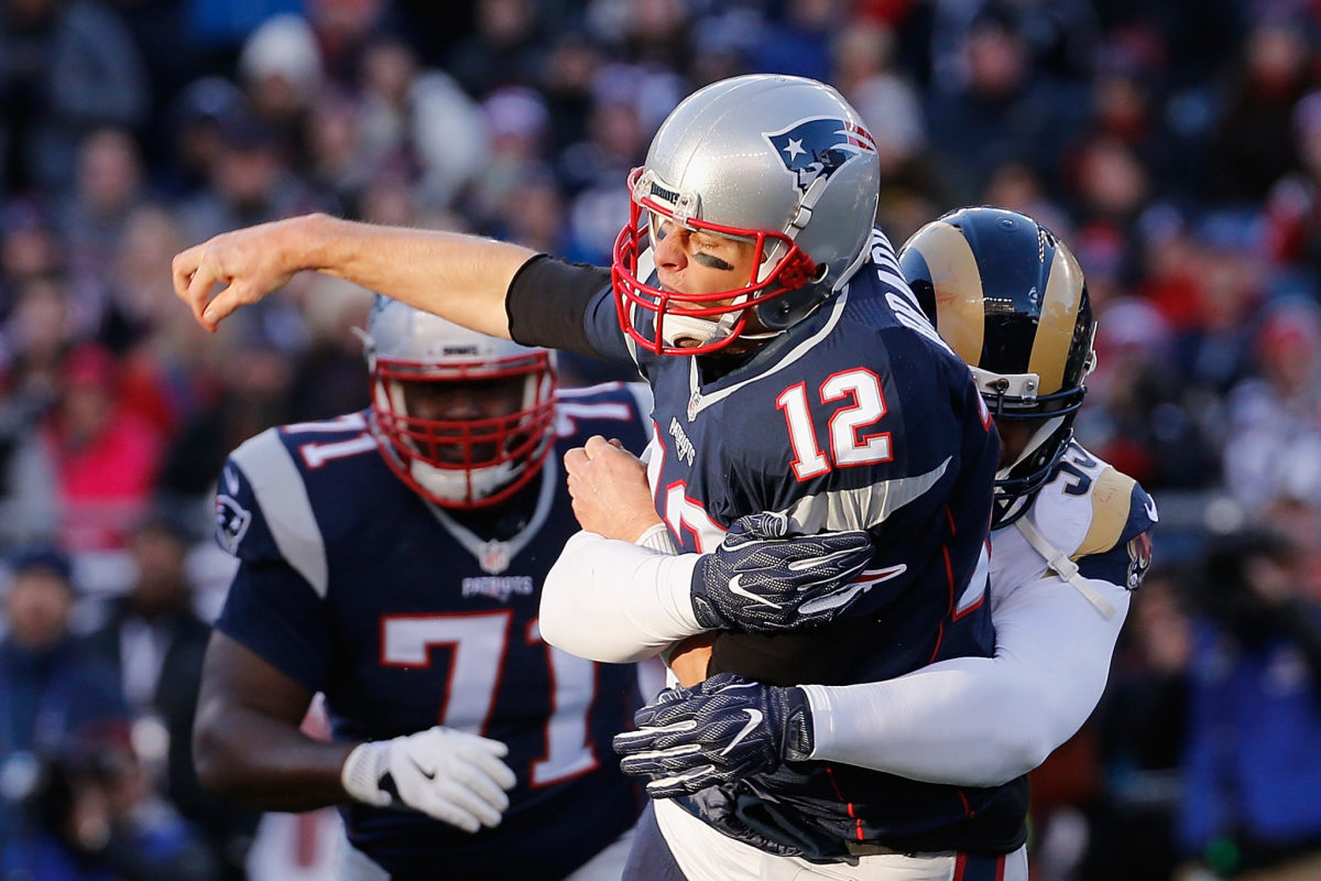 FOXBORO, MA - DECEMBER 04:  Tom Brady #12 of the New England Patriots is hit by Ethan Westbrooks #93 of the Los Angeles Rams during their game at Gillette Stadium on December 4, 2016 in Foxboro, Massachusetts.  (Photo by Jim Rogash/Getty Images)