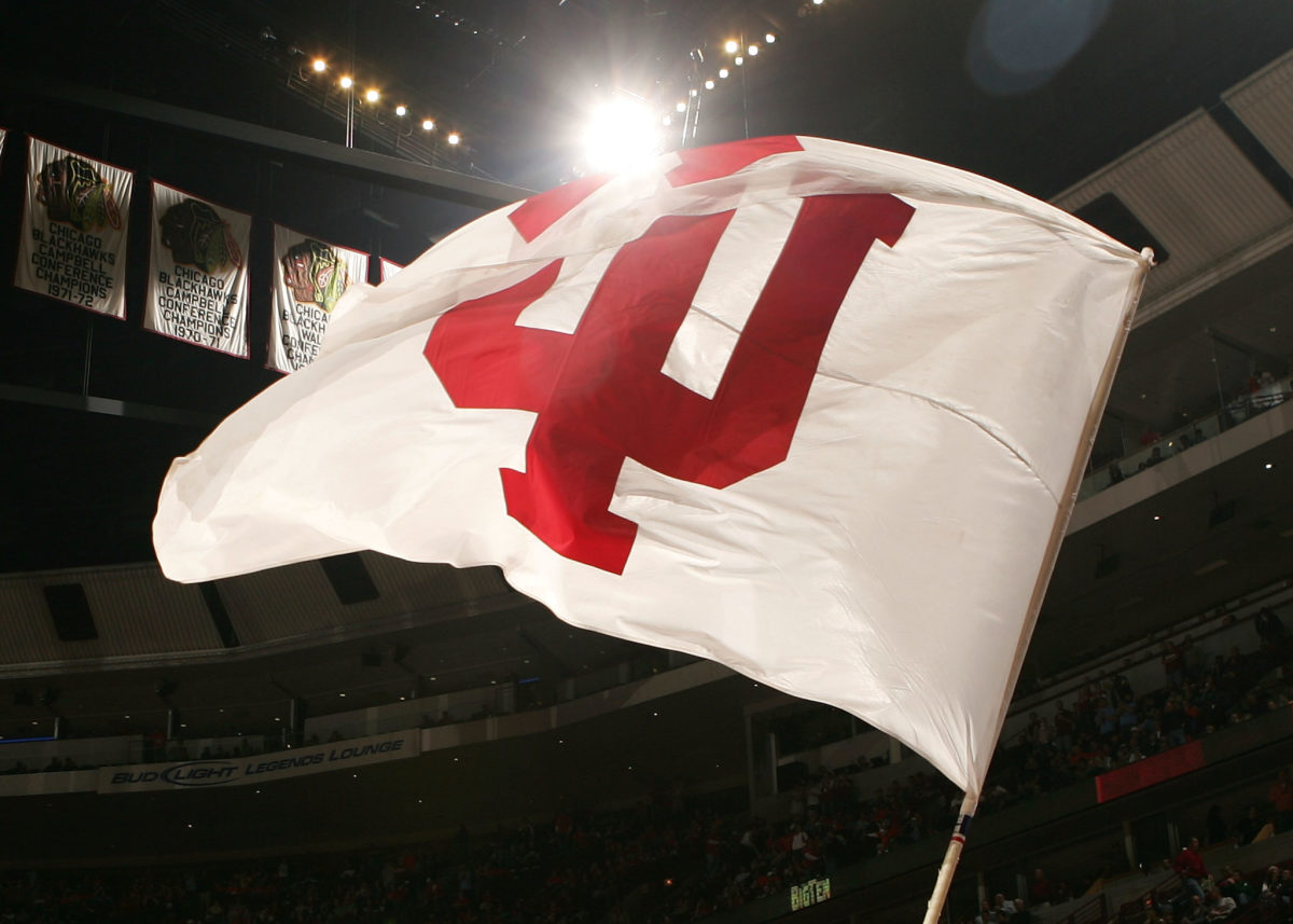 A cheerleader from the Indiana Hoosiers waves a flag with Indiana's logo on the court against the Illinois Fighting Illini.