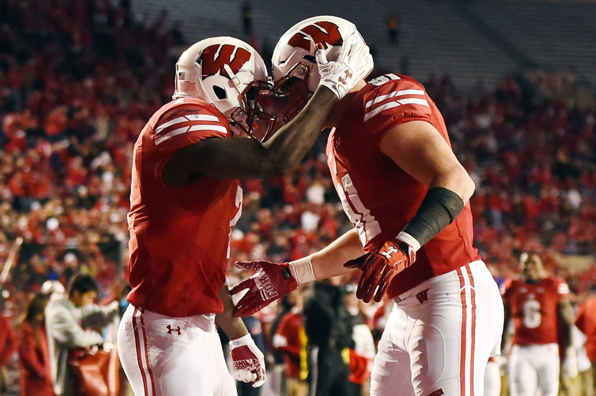 Two Wisconsin including running back Bradrick Shaw players bang helmets to celebrate a touchdown.