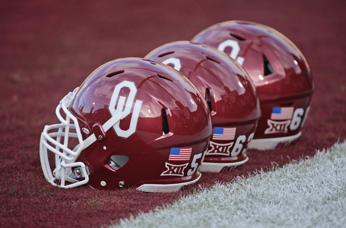 A closeup of three Oklahoma Sooners football helmets on the field before a football game.