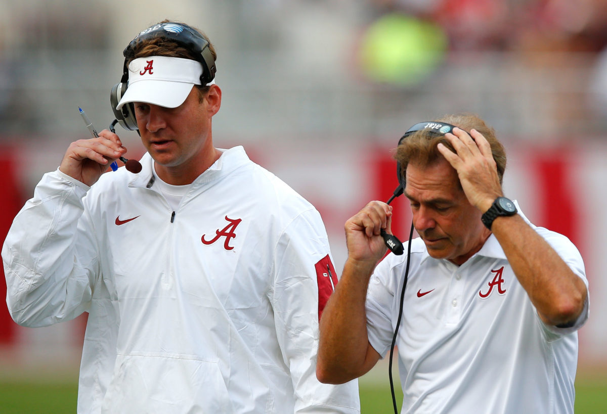 Nick Saban and Lane Kiffin talking into their headsets.