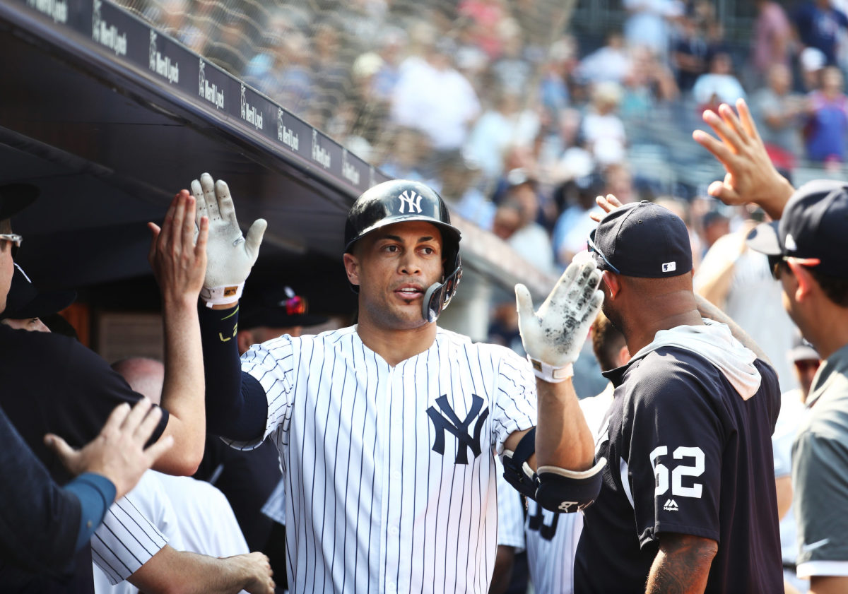 New York Yankees OF Giancarlo Stanton celebrating in the dugout with his teammates.