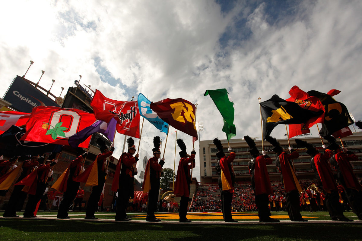 Members of a marching band holding up flags representing Big Ten schools.